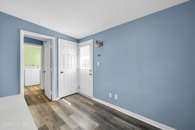 empty room featuring baseboards, dark wood-style floors, and washer / clothes dryer
