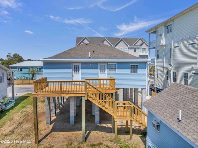 back of property with stairway, a deck, roof with shingles, and a carport