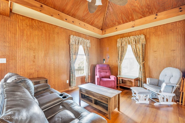 living area with wooden walls, wood ceiling, a ceiling fan, and wood finished floors