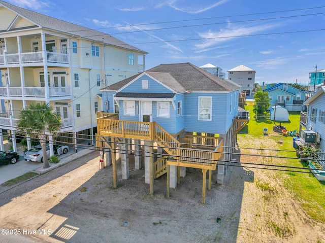 coastal inspired home featuring roof with shingles, fence, a residential view, a carport, and driveway