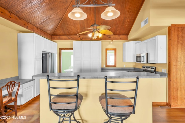 kitchen featuring visible vents, wood finished floors, wooden ceiling, vaulted ceiling, and stainless steel appliances