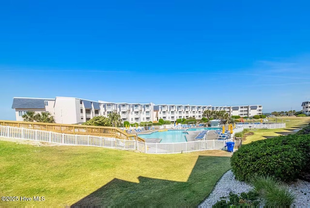 community pool featuring a lawn and fence