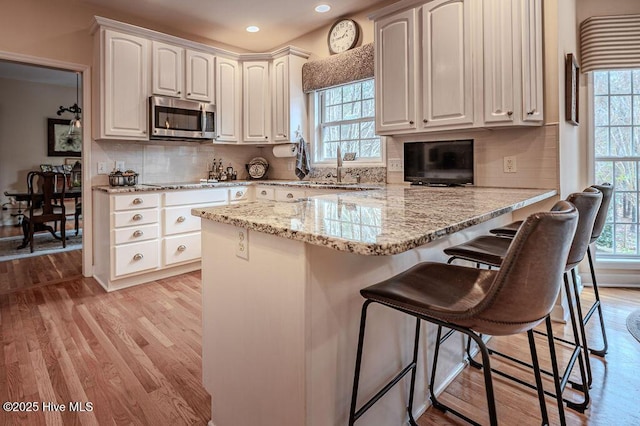 920 Diamondhead Dr S, Pinehurst, NC 28374 - kitchen featuring a peninsula, stainless steel microwave, a wealth of natural light, and light wood-type flooring