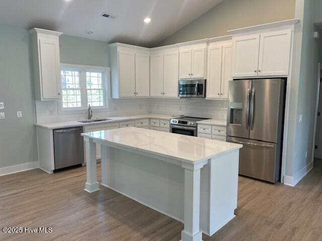 189 Boundaryline Dr NW, Calabash, NC 28467 - kitchen with stainless steel appliances, a sink, a center island, light wood-style flooring, and white cabinets