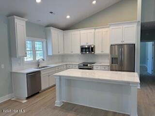 189 Boundaryline Dr NW, Calabash, NC 28467 - kitchen with appliances with stainless steel finishes, a sink, vaulted ceiling, light countertops, and tasteful backsplash