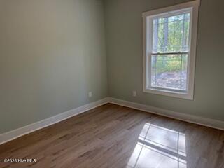 unfurnished room with baseboards and dark wood-style flooring