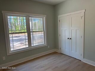 unfurnished bedroom with baseboards, a closet, and wood finished floors