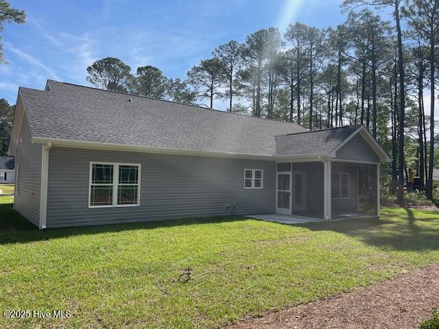 189 Boundaryline Dr NW, Calabash, NC 28467 - rear view of house with a sunroom, a lawn, and roof with shingles