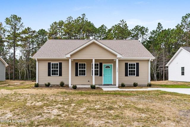 single story home featuring covered porch, a shingled roof, and a front lawn