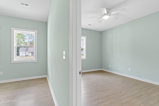 spare room with baseboards, ceiling fan, wood finished floors, and visible vents