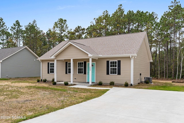 ranch-style home with roof with shingles, a porch, central AC, and a front yard
