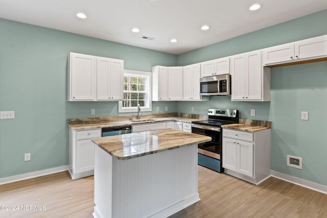 kitchen with visible vents, a sink, light stone counters, stainless steel appliances, and white cabinetry