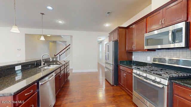 kitchen featuring baseboards, dark wood-style floors, a sink, appliances with stainless steel finishes, and decorative light fixtures