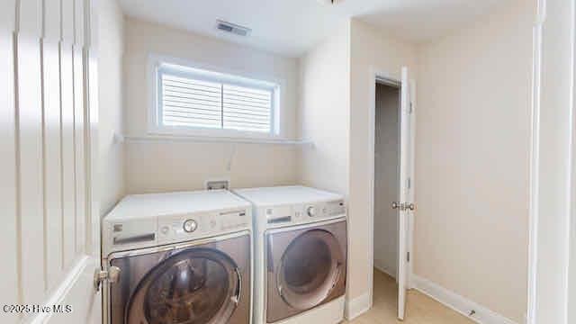 clothes washing area with washing machine and dryer and visible vents
