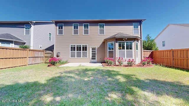 back of property with a patio, a fenced backyard, and a yard