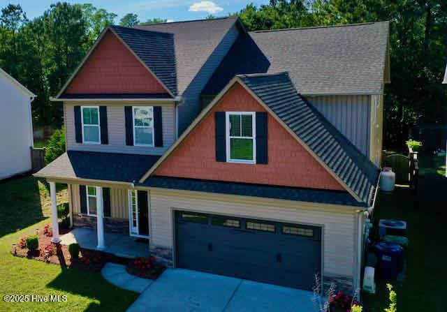 craftsman-style house with covered porch, concrete driveway, a front yard, and a garage