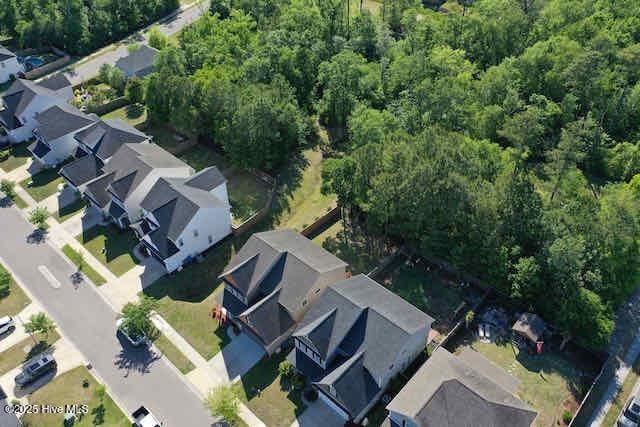 drone / aerial view featuring a wooded view and a residential view