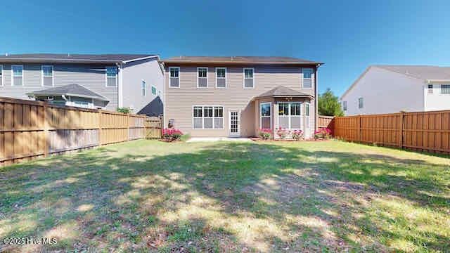 back of house featuring a yard and a fenced backyard