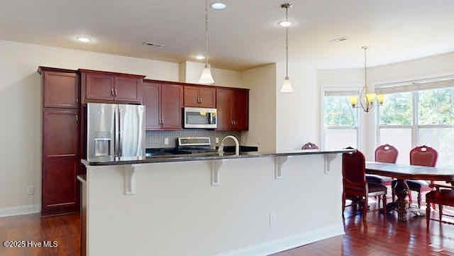 kitchen with appliances with stainless steel finishes, baseboards, a breakfast bar area, and dark wood-style floors