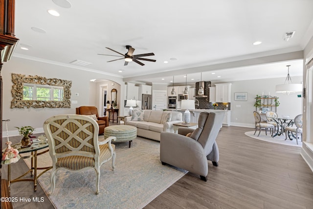 living room with arched walkways, ceiling fan, wood finished floors, and visible vents