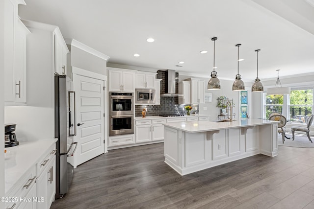kitchen featuring appliances with stainless steel finishes, a sink, dark wood finished floors, wall chimney exhaust hood, and white cabinetry