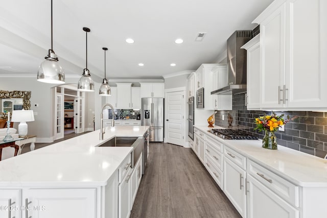 kitchen with crown molding, stainless steel appliances, a sink, and wall chimney exhaust hood