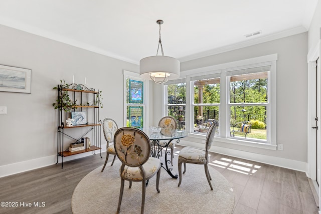 dining space featuring a healthy amount of sunlight, ornamental molding, and wood finished floors