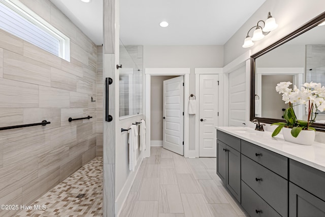 bathroom featuring vanity, baseboards, walk in shower, and recessed lighting