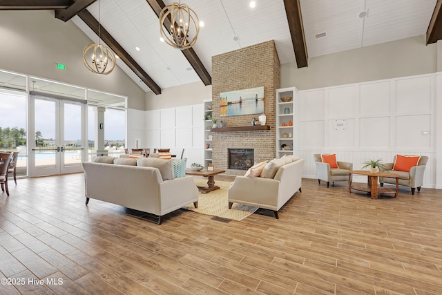 living room with an inviting chandelier, beam ceiling, a decorative wall, and high vaulted ceiling