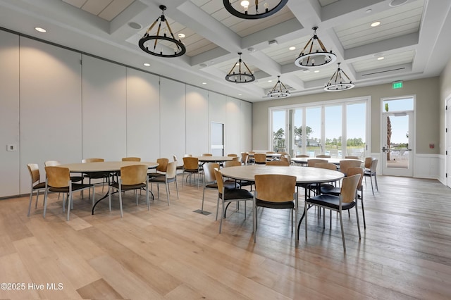 dining room with a decorative wall, beam ceiling, light wood-style floors, a chandelier, and coffered ceiling