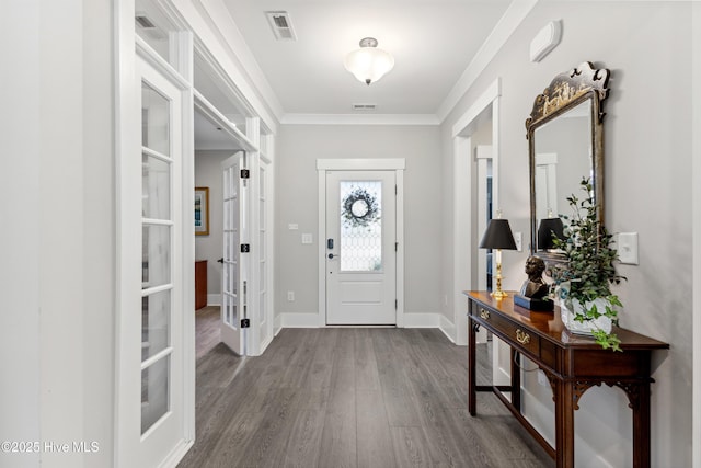 entryway with baseboards, visible vents, ornamental molding, and wood finished floors