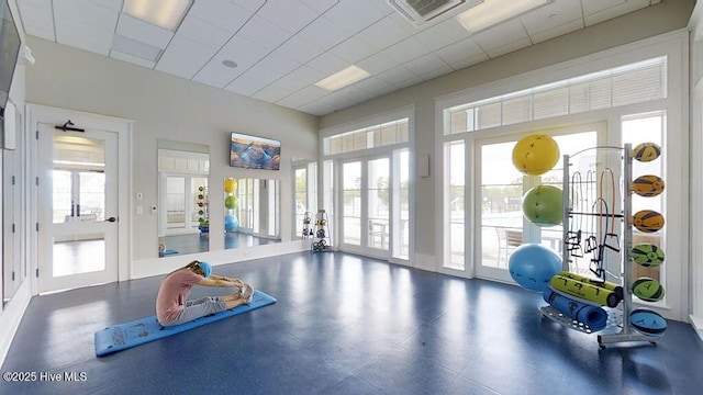 workout area featuring french doors, a paneled ceiling, a healthy amount of sunlight, and visible vents