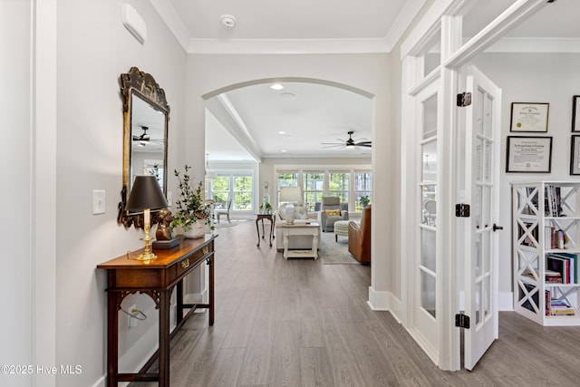 hallway with french doors, arched walkways, crown molding, and wood finished floors