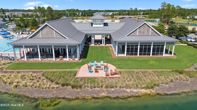 back of property featuring a lawn, a water view, metal roof, and a patio area