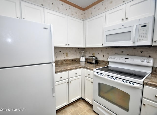 kitchen featuring crown molding, dark countertops, white cabinets, and white appliances