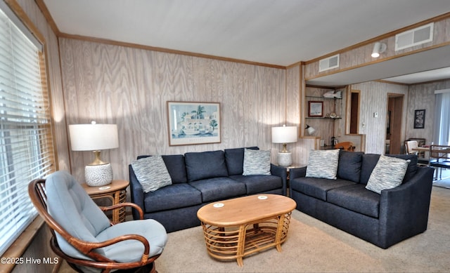 living room featuring visible vents, wood walls, crown molding, and carpet floors