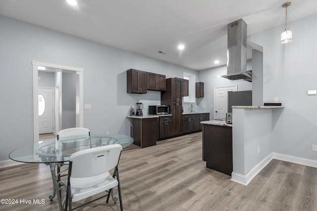 kitchen with light wood-style floors, range hood, stainless steel appliances, and dark brown cabinets