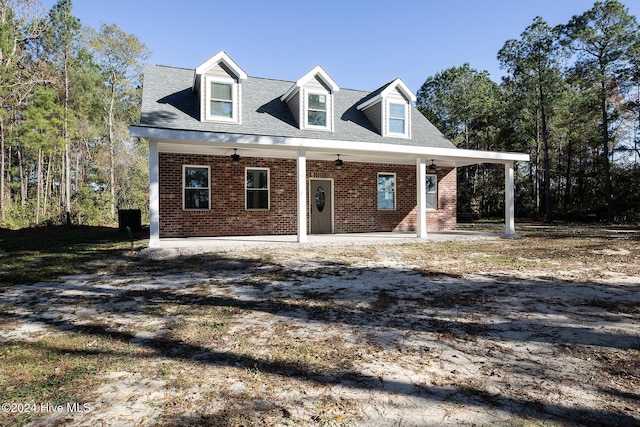 cape cod home featuring brick siding, a shingled roof, and a porch