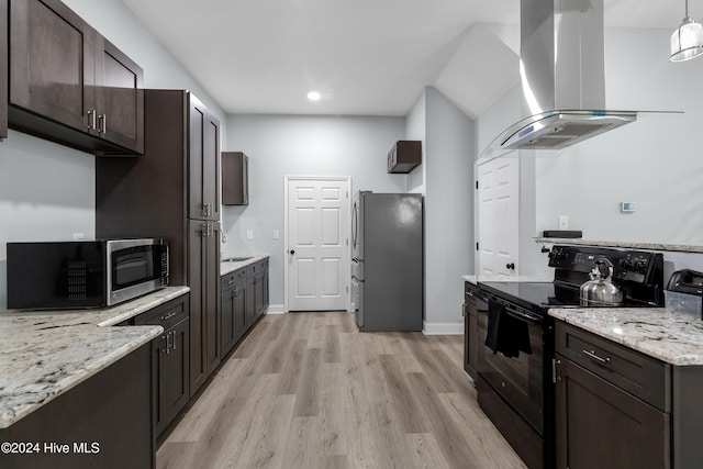 kitchen featuring wall chimney range hood, dark brown cabinetry, appliances with stainless steel finishes, light stone countertops, and light wood-style flooring