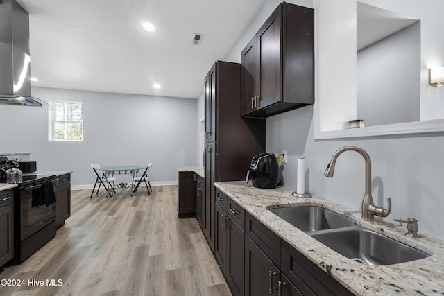kitchen featuring black / electric stove, light wood-type flooring, a sink, recessed lighting, and wall chimney exhaust hood