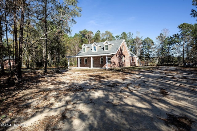 new england style home with a porch and brick siding