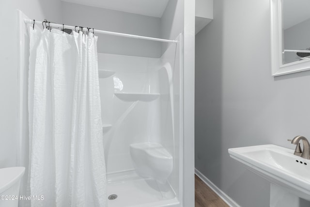 bathroom featuring toilet, a shower stall, a sink, and wood finished floors
