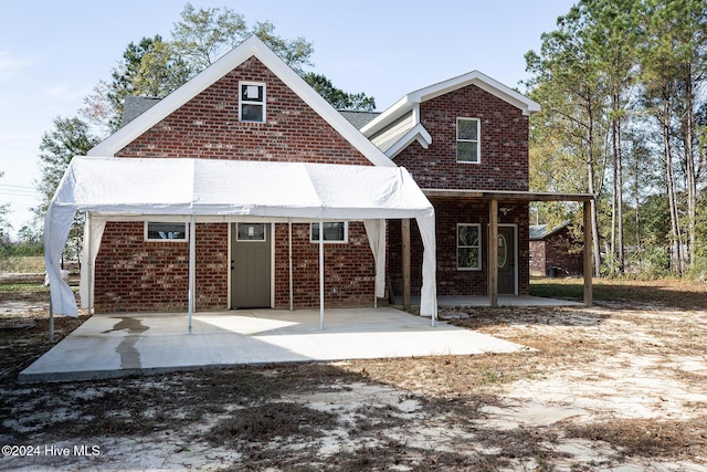 rear view of property with brick siding and a patio