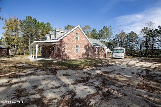 view of home's exterior featuring brick siding, a ceiling fan, and driveway
