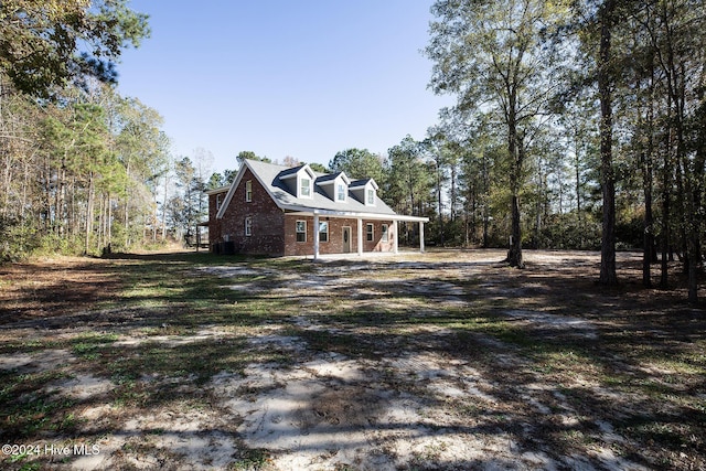 view of side of property featuring brick siding and covered porch