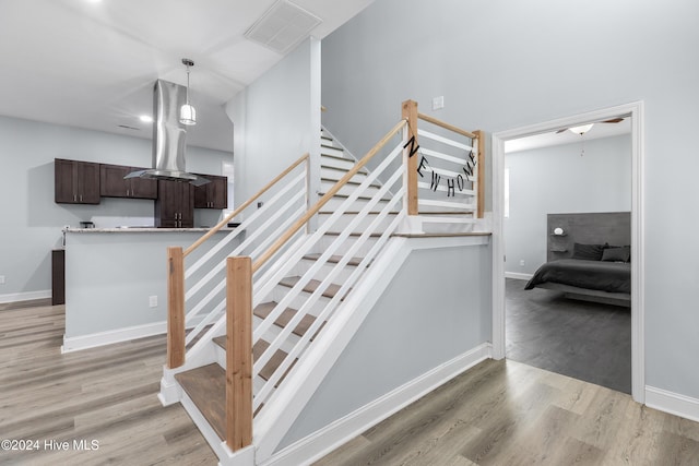 staircase with baseboards, wood finished floors, and visible vents