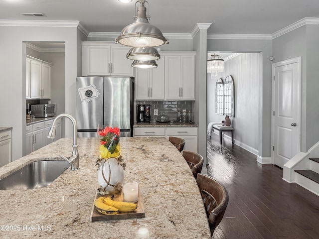 7845 Champlain Dr, Wilmington, NC 28412 - kitchen with a kitchen bar, dark wood-style flooring, light stone countertops, a sink, and stainless steel appliances