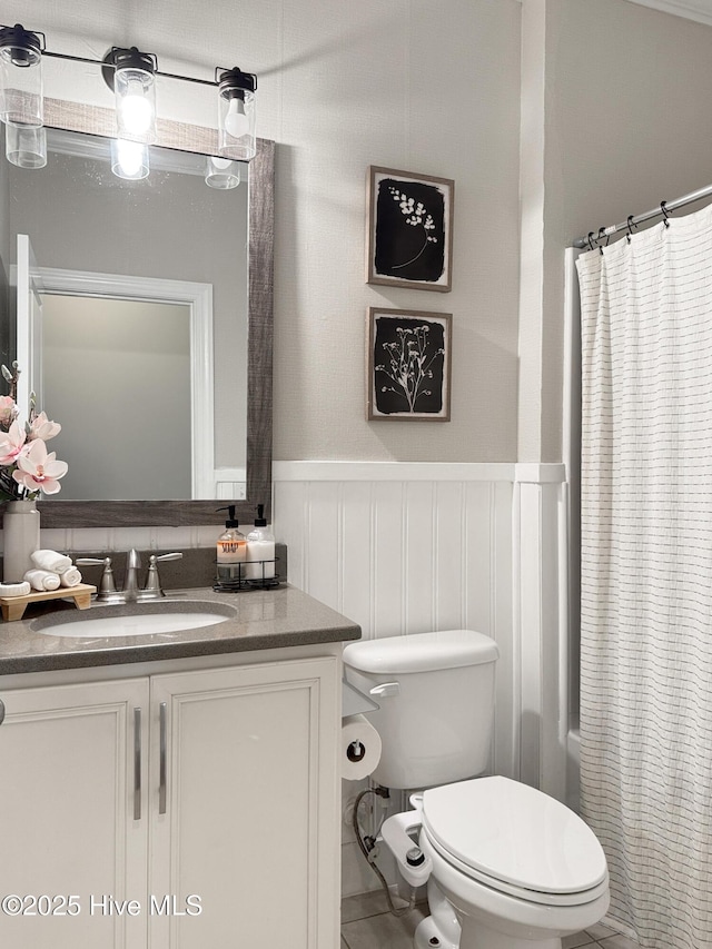 7845 Champlain Dr, Wilmington, NC 28412 - full bathroom featuring vanity, wainscoting, a decorative wall, and toilet