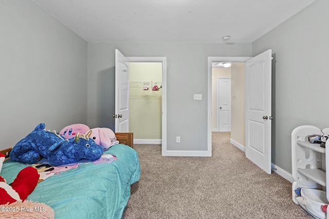 bedroom featuring baseboards, carpet flooring, and a walk in closet