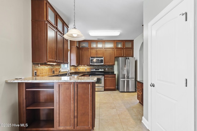 kitchen with decorative backsplash, a peninsula, light stone counters, hanging light fixtures, and stainless steel appliances